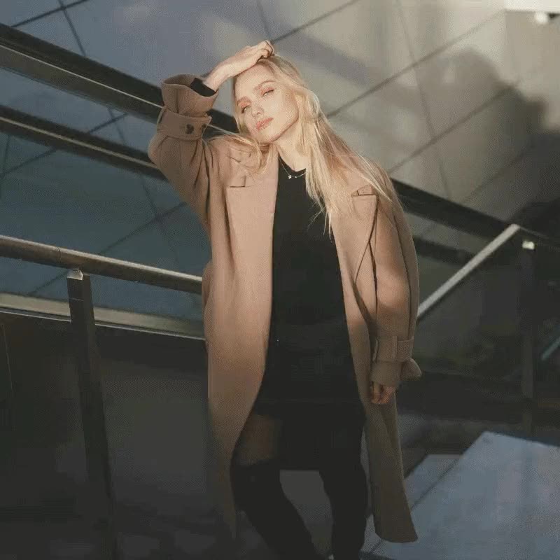 Editorial portrait: model in a camel coat on a sunlit staircase